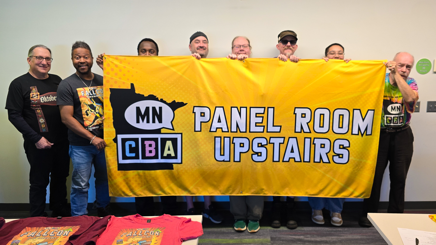 photo of volunteers holding the large 8 foot by 4 foot panel room banner inside a meeting room