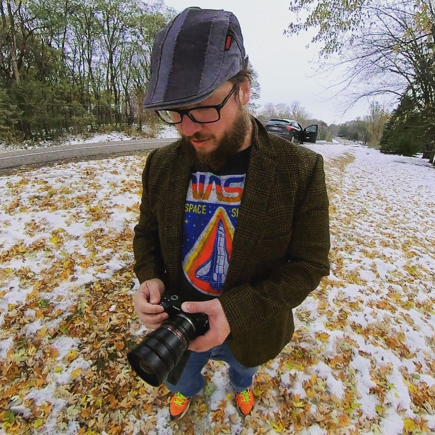 Rusty Detty photo of Rusty Detty holding a DSLR camera while standing in snowed-over fall leaves