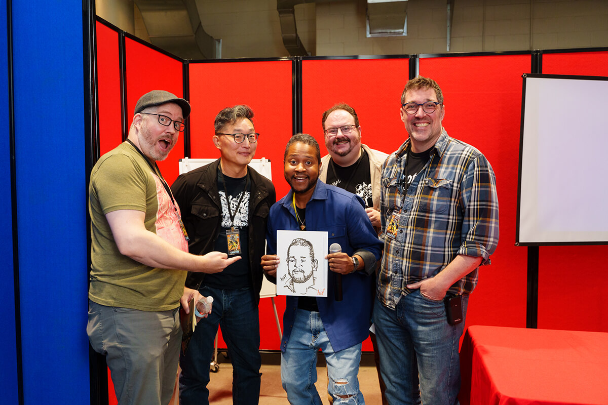Group photo in the panel room at MNCBA FallCon 2024. Left to right: John Bivens, Gene Ha, Eric Childs, Ted Anderson, and Zander Cannon. Photo by Buzz Meade. group of comic creators and panel moderator standing in front of red and blue walls and a projector screen